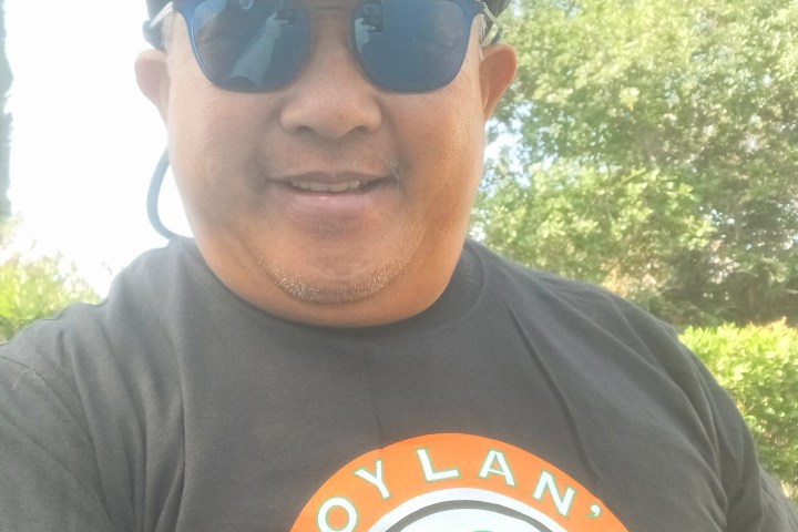 a man wearing a hat and sunglasses posing for the camera