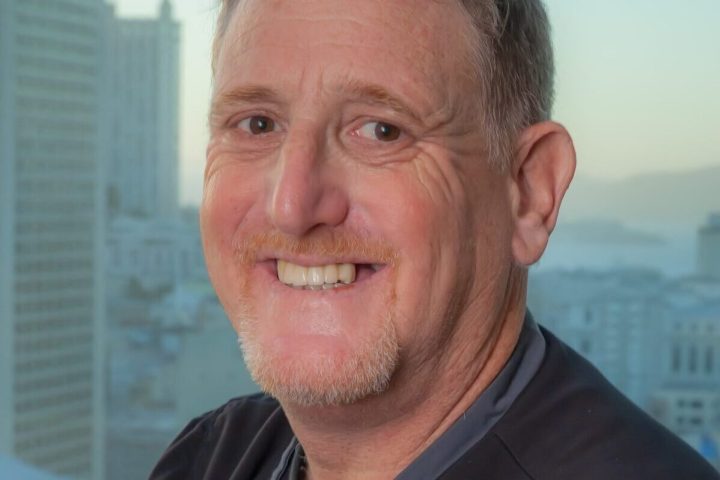 a man wearing glasses and smiling at the camera